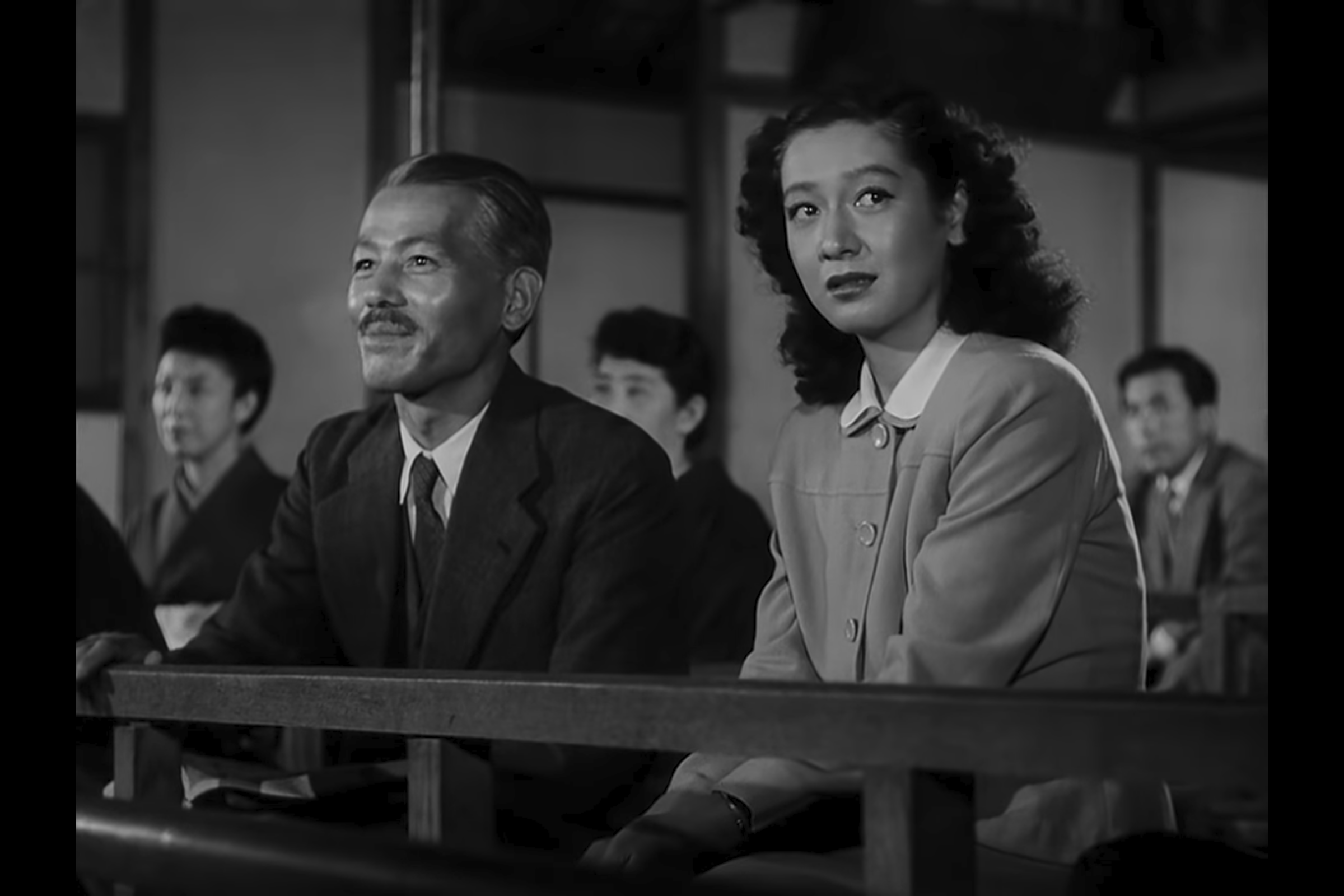 Persistence without Force: Mrs. Miwa bows to Somiya in the audience while Noriko lowers her head, registering her father’s separateness and the fragility of their shared world.
